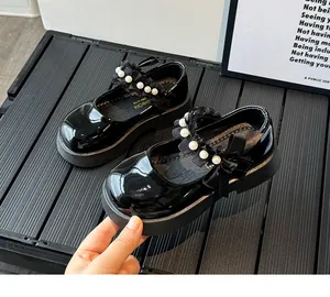 Detail of girls' black patent leather Mary Janes with pearls, lace, and bow accents