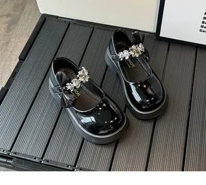 Vue détaillée des babies en cuir verni noir avec nœud floral orné de strass brillants