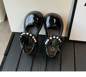 Macro detail of glossy black Mary Jane shoes with pearl straps and lace butterfly trim