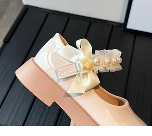 Detail of white patent leather Mary Jane shoes with ribbon bow and pearl trim