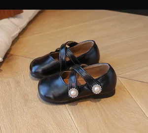 Detailansicht der schwarzen Mary-Jane-Schuhe mit Perlenblumen auf Holzhintergrund