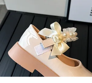 Detail of girls' Mary Jane shoe showing lace, silk bow, pearls and velcro strap