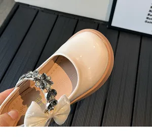 Détail de chaussure Mary Jane crème avec fleur en strass et nœud élégant pour fille