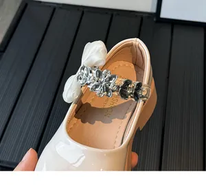 Gros plan de chaussures Mary Jane beiges pour filles avec fleurs en strass et nœuds
