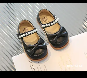 Detail of girls' black Mary Jane leather shoes with pearl bow and round toe design