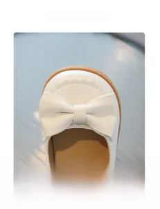 Detailaufnahme weißer Mädchenschuhe aus Rindspaltleder mit Schleife und Wellenrand