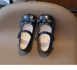 Close-up of black Mary Jane girls shoes with a bow knot and velcro strap detail