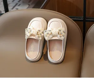 Detailed close-up of girls' pearled bow mule with rhinestones on cream leather shoe