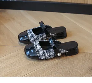 Detail of girls' tweed Mary Jane mules with black patent leather toe and pearl accent