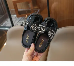 Detail of girls' black patent leather mule shoes with large pearl and rhinestone bow