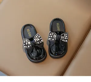 Detail of black patent leather girls' loafers featuring pearls and rhinestone bow