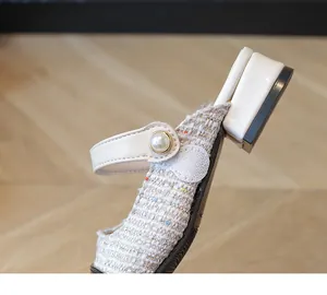 Detail of girls' princess sandal featuring pearl buckle and colorful woven fabric texture