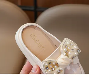 Detail of children's cream slippers with pearl rhinestone bow and MG.BABY logo