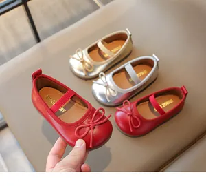 Close-up of children's Mary Jane shoes with bow detail in red, silver, and gold colors