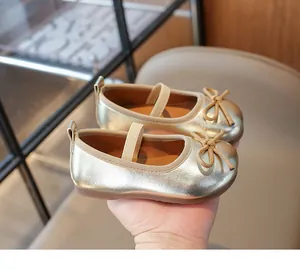Close-up of golden metallic girls' Mary Jane shoes featuring a bow and elastic strap
