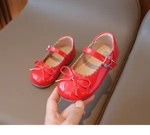 Detalle de zapatos Mary Jane de charol rojo con lazo delicado y hebilla con forma de corazón