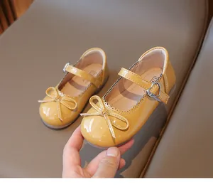 Detalle de zapatos de charol amarillo para niños con lazo y hebilla de corazón