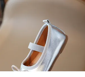 Detail of silver metallic Mary Jane girl's shoe with elastic strap and bow accent