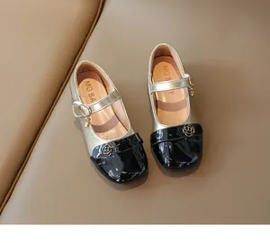 Dettaglio di scarpe Mary Jane da bambina con camelie dorate e punta in vernice nera