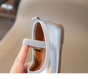 Detail of silver metallic girl shoe showing elastic strap and flexible inner lining