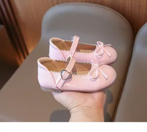 Primer plano de zapatos de charol rosa para niñas con lazo y detalle de borde festoneado