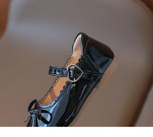Detalle de zapatos Mary Jane de charol negro para niñas con hebilla de corazón y lazo