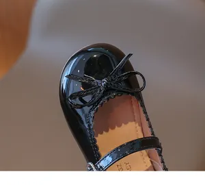 Detalle de zapatos de charol negro para niñas con lazo y bordes festoneados finos