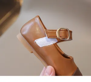 Detail of girls' brown Mary Jane shoe showing smooth leather texture and metal buckle
