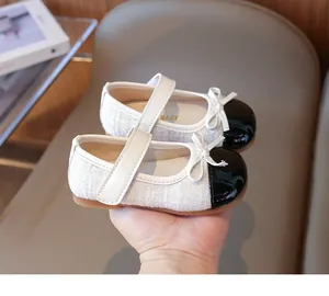 Close-up of girls Mary Jane shoes featuring tweed fabric and patent leather toe with bow