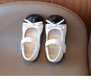 Close-up of girls' Mary Jane shoes featuring black patent leather and white tweed texture