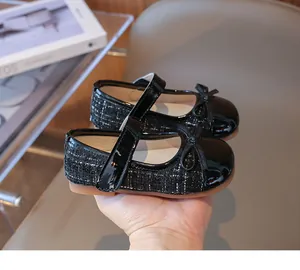 Detail of girls black Mary Jane shoe showing tweed fabric and patent leather bow