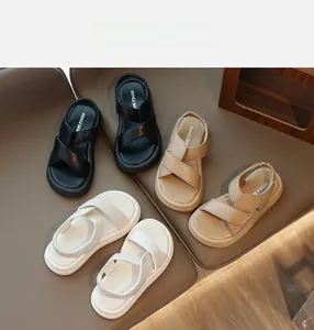 Dettaglio di sandali per bambini in nero, beige e bianco con cinturino elastico