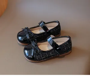 Detail of girls' black tweed Mary Jane shoes with patent leather bow and non-slip sole