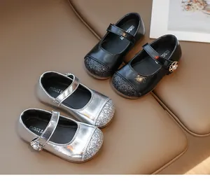 Close-up of glitter sequins and pearl flower buckle on girls silver and black Mary Jane shoes