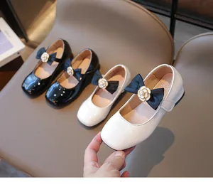 Detail von Mädchen Mary Janes aus Lackleder mit Seidenschleifen und Kamelienblüten