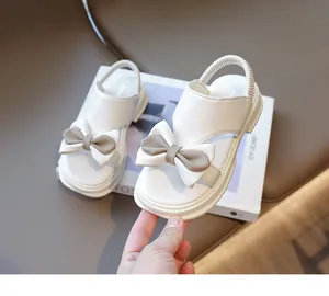 Nahaufnahme weißer Mädchensandalen mit Schleifenverzierung und elastischem Fersenriemen