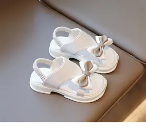 Detail von weißen Mädchensandalen mit grauer Schleife und elastischem Band