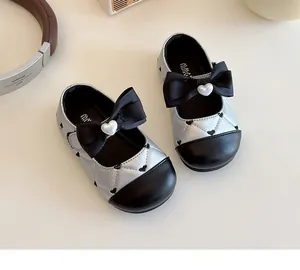 Détail de babies filles avec motif matelassé, nœud noir et décor de perle en cœur