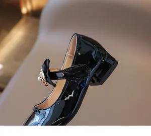 Detailaufnahme von schwarzen Mädchen-Lacklederschuhen mit Schleife und Perlen-Schnalle
