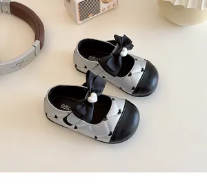 Vue détaillée des babies matelassées argentées pour filles avec nœuds noirs et cœurs