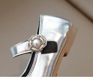 Close-up of silver sequin Mary Jane shoes featuring pearl flower buckle and velcro strap