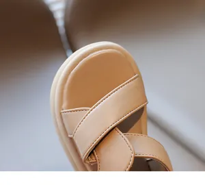Dettaglio di sandali beige in pelle per bambini con suola morbida e cinturini incrociati