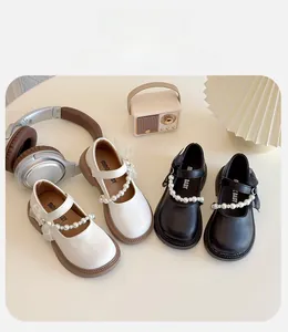 Detail of girls' Mary Jane shoes with pearl straps and mesh bows in black and beige