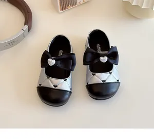 Gros plan de chaussures bébé matelassées argentées avec nœud noir et perle cœur
