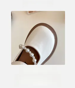Detail of cream girls Mary Jane shoes featuring large pearls and rhinestone strap