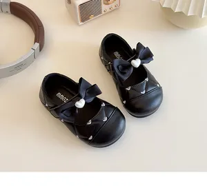Détail de babies matelassées pour filles avec nœud noir et perle en forme de cœur