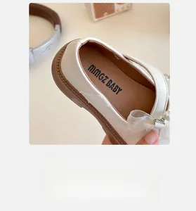 Close-up of girl's white Mary Jane shoe featuring breathable lining and pearl bow detail