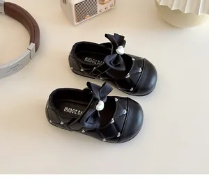 Détail de chaussures Mary Jane noires avec motif matelassé et nœud à perle cœur