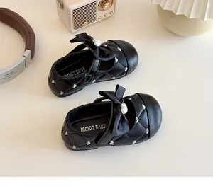 Détail de chaussures Mary Jane noires matelassées avec broderie coeur et perle