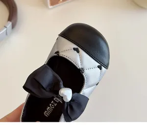 Vue détaillée de chaussures argentées matelassées avec broderie cœur et nœud noir